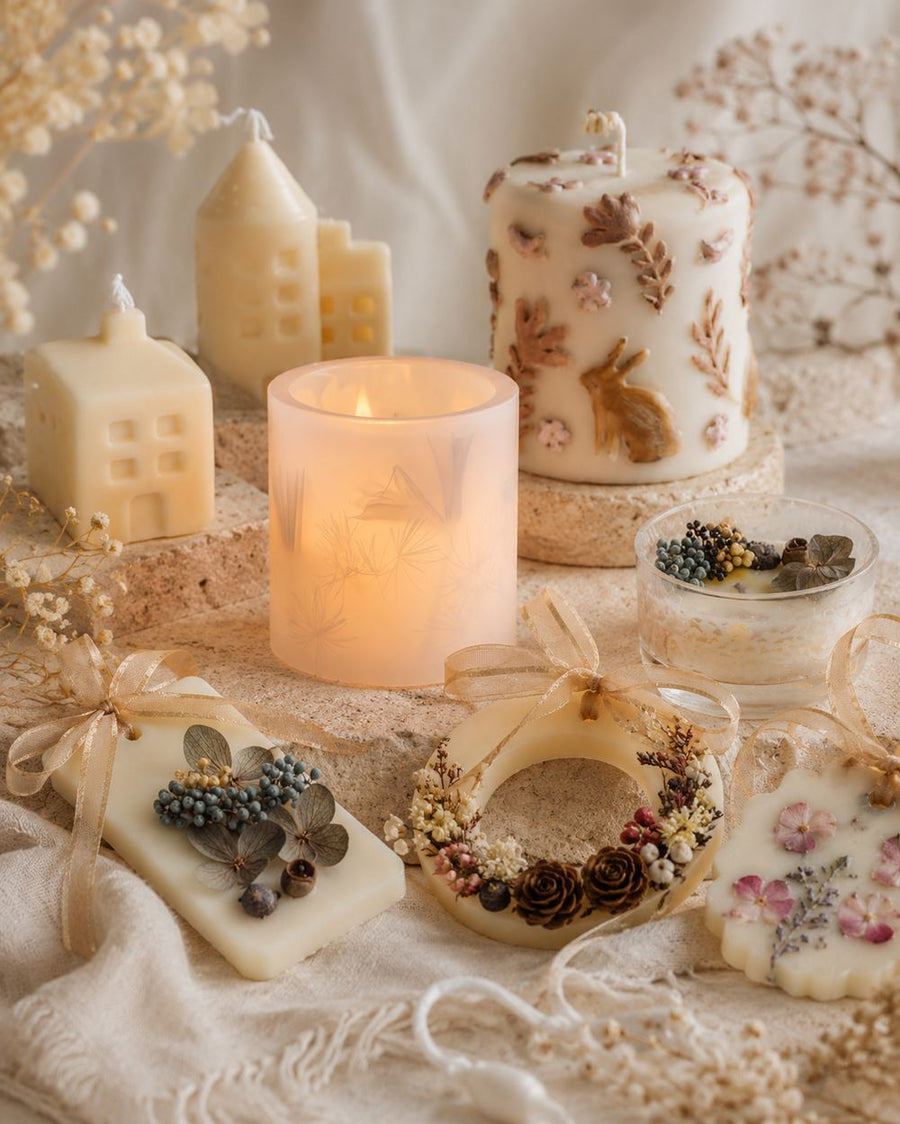 Floral candle and wax ornaments styled on warm linen